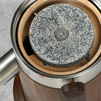 Der drehende Mahlstein aus Granit in einer Mahlkammer aus Holz