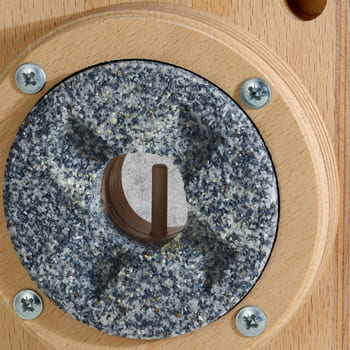 Der obere, stehende Mahlstein mit Einfassung ist am Trichtereinsatz befestigt.